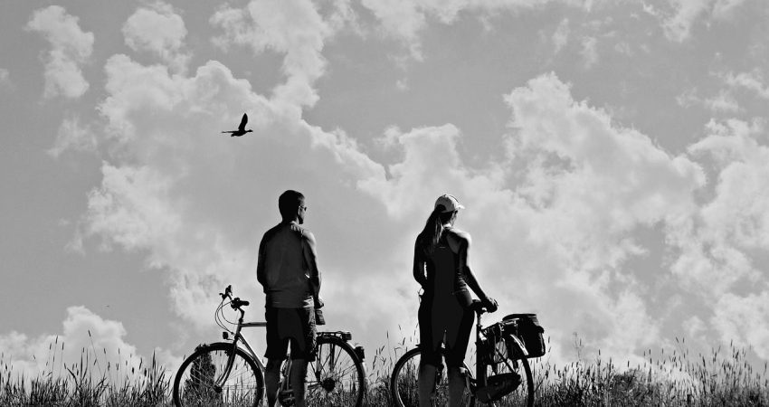 Zwei Radfahrer*innen vor wolkigem Himmel